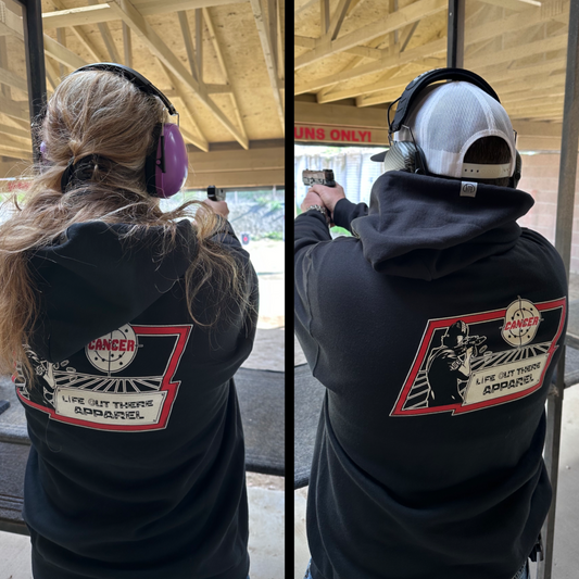 Life Out There Apparel “Kill Cancer” Black Unisex hoodie has picture of a man shooting a sign that says cancer on it & the bullet rounds coming out of the gun have  “chemo” written on them. This is a man and women showing the back of the hoodie.  