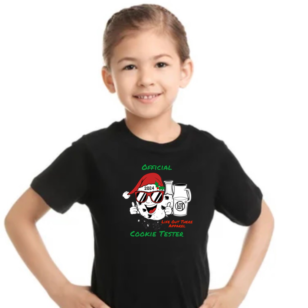 Black short sleeve youth t-shirt with a cartoon cookie wearing a Santa hat and sunglasses labeled "2024," alongside glass milk cartons. Text reads, "Life Out The Apparel / official cookie tester”.