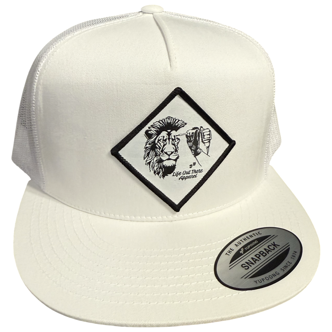 The Not All There - Flat Bill SnapBack Trucker Hat in white by Life Out There Apparel features a mesh back, flat brim, diamond-shaped lion and fist patch, “Life Out There Magazine” text, and subtle NOT ALL THERE details.