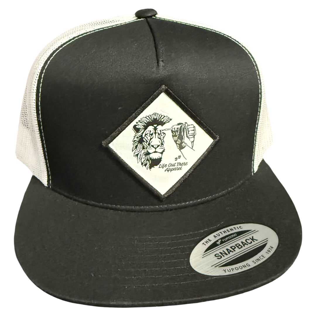 The Not All There - Flat Bill SnapBack Trucker Hat in black and white by Life Out There Apparel features a patch with a lion sketch, fist bump, and NOT ALL THERE. Mesh back; brim sticker reads The Authentic Snapback Yupoong Since 1974.