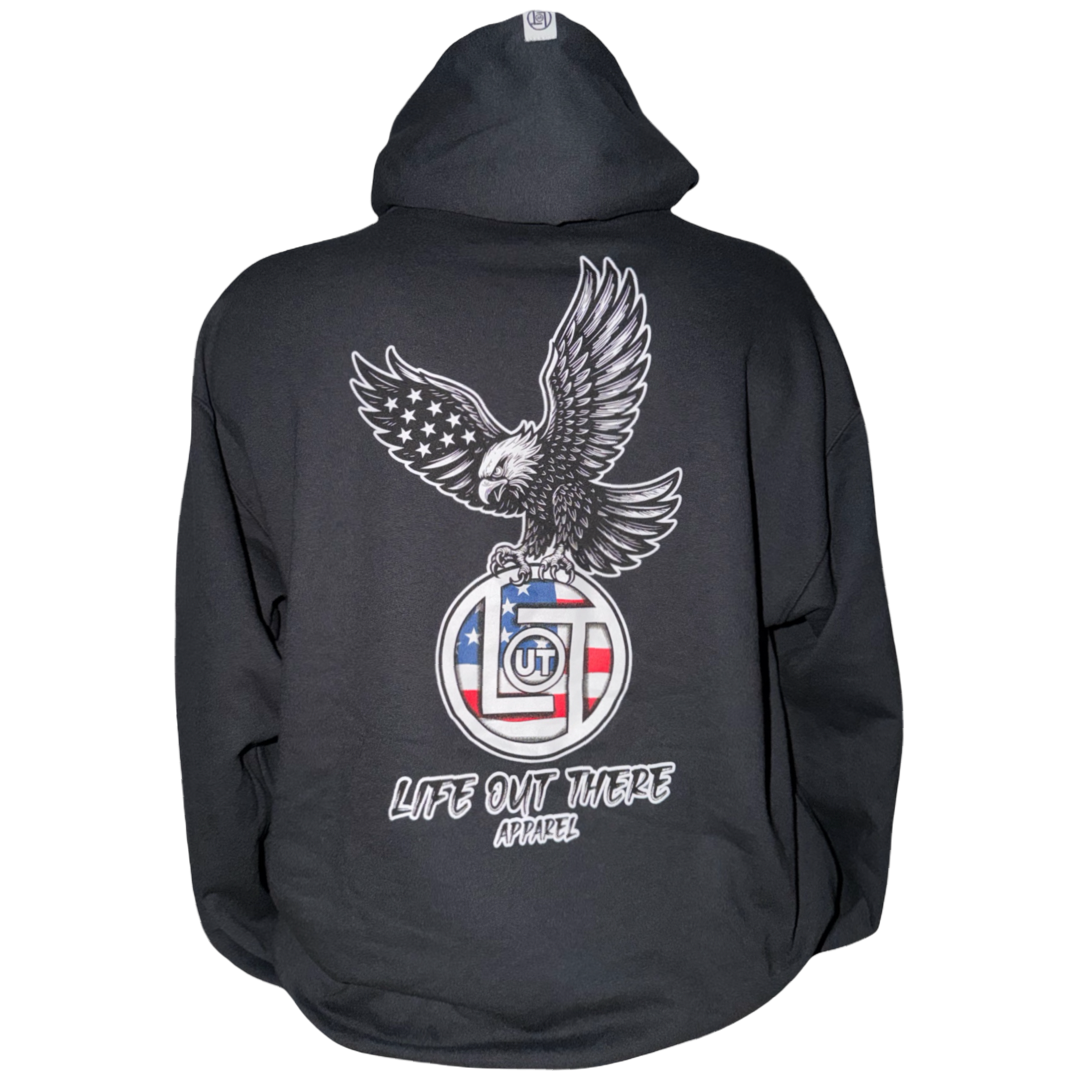 The Flight of Freedom Hoodie - Black by Life Out There Apparel is a unisex, tagless hoodie in a soft cotton-poly blend, boasting a bold eagle graphic and American flag plus prominent LIFE OUT THERE APPAREL print.