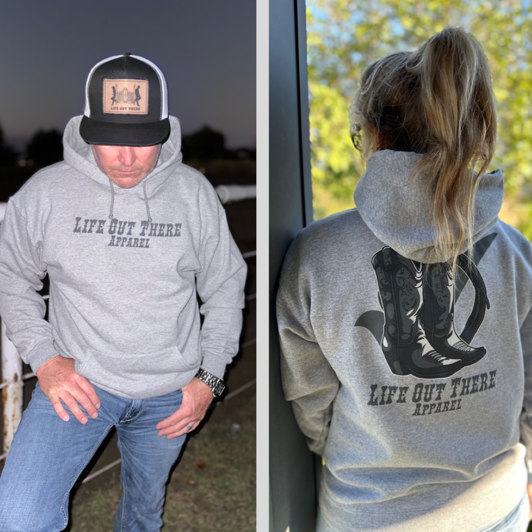 Two images depict an individual wearing the Unisex Boot Check Hoodie in Oxford Grey by Life Out There Apparel. The front of the hoodie is plain, while the back showcases a BOOT CHECK design with cowboy boots. The person completes the look with a cap and jeans, standing in an outdoor setting.