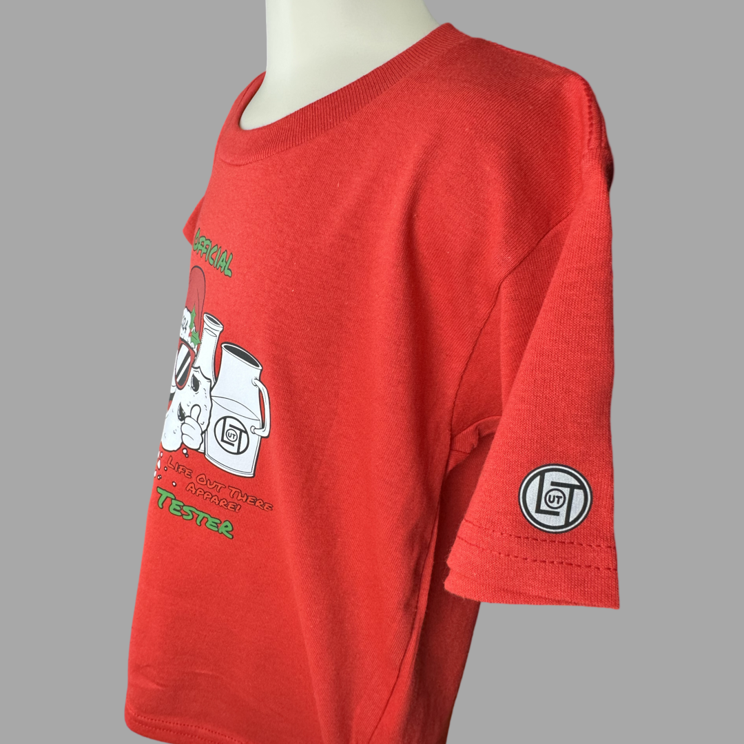Red short sleeve toddler t-shirt with a cartoon cookie wearing a Santa hat and sunglasses labeled "2024," alongside glass milk cartons. Text reads, "Life Out The Apparel / official cookie tester”.