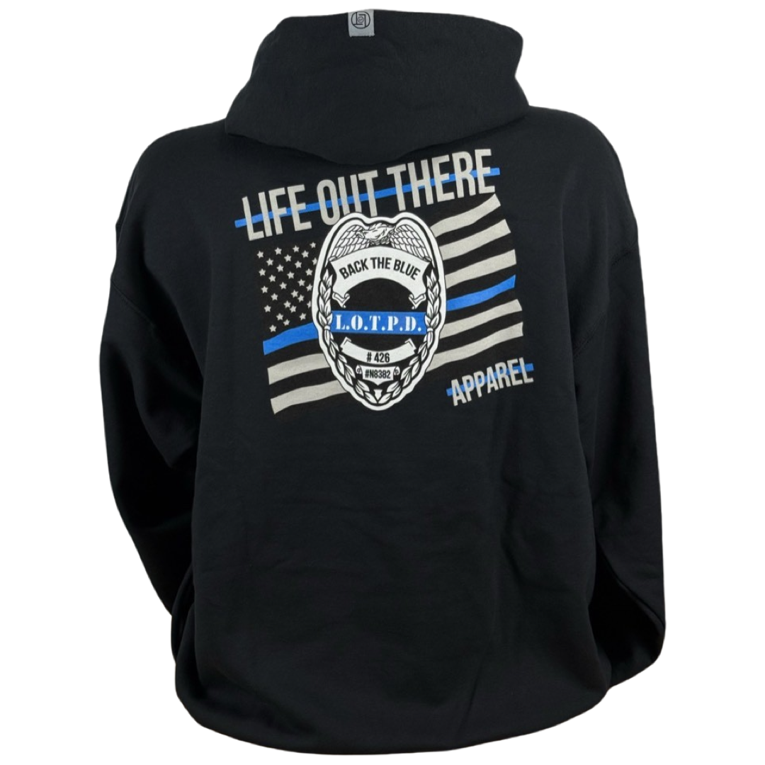 Back view of the Unisex - Back The Blue Hoodie in black by Life Out There Apparel, featuring a polyester-cotton blend with a central L.O.T.P.D. badge and an American flag design, along with bold white and blue text displaying BACK THE BLUE, LIFE OUT THERE, and APPAREL.