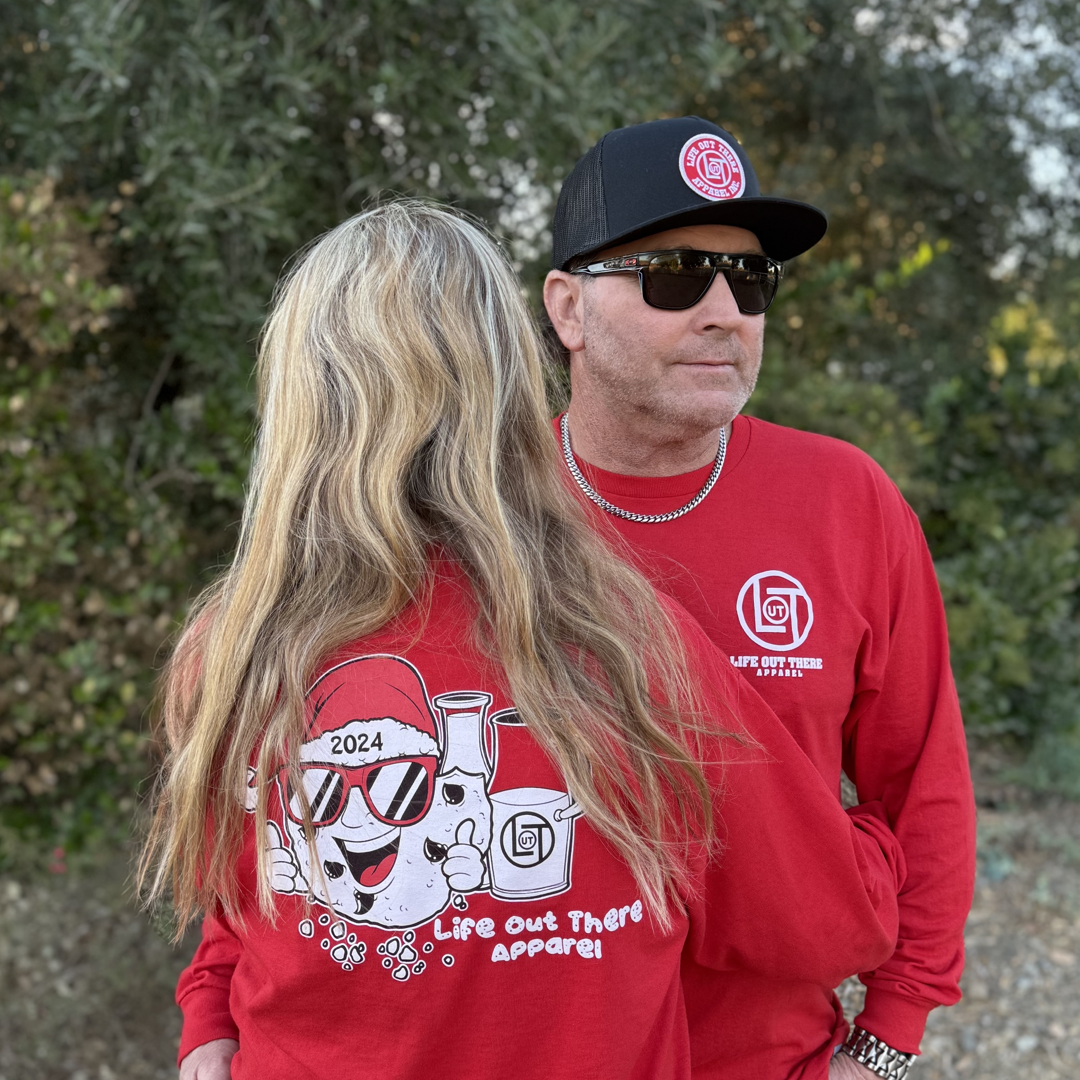 Red shirt with a cartoon cookie wearing a Santa hat and sunglasses labeled "2024," alongside glass milk cartons. Text reads, "Life Out The Apparel.