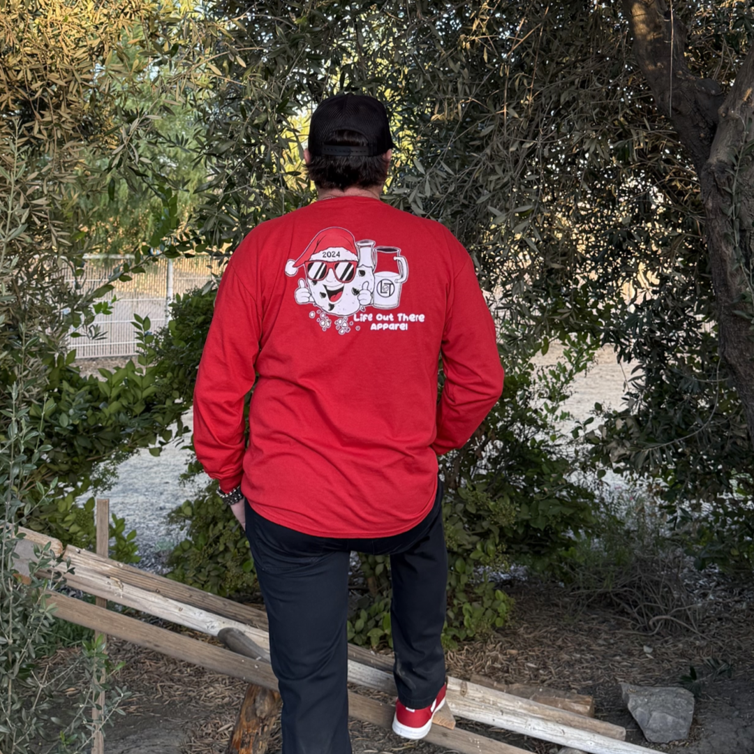 Red shirt with a cartoon cookie wearing a Santa hat and sunglasses labeled "2024," alongside glass milk cartons. Text reads, "Life Out The Apparel.