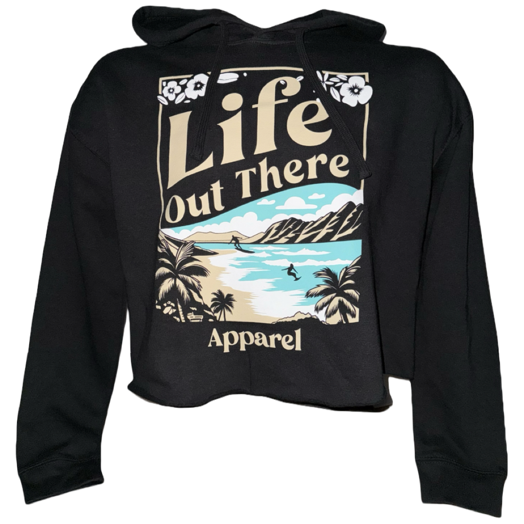 The Womens Aloha Crop Hoodie in Black by Life Out There Apparel features a graphic of a tropical beach, palm trees, mountains, and ocean with Life Out There Apparel text, inspired by Oahus North Shore for true Hawaiian vibes.
