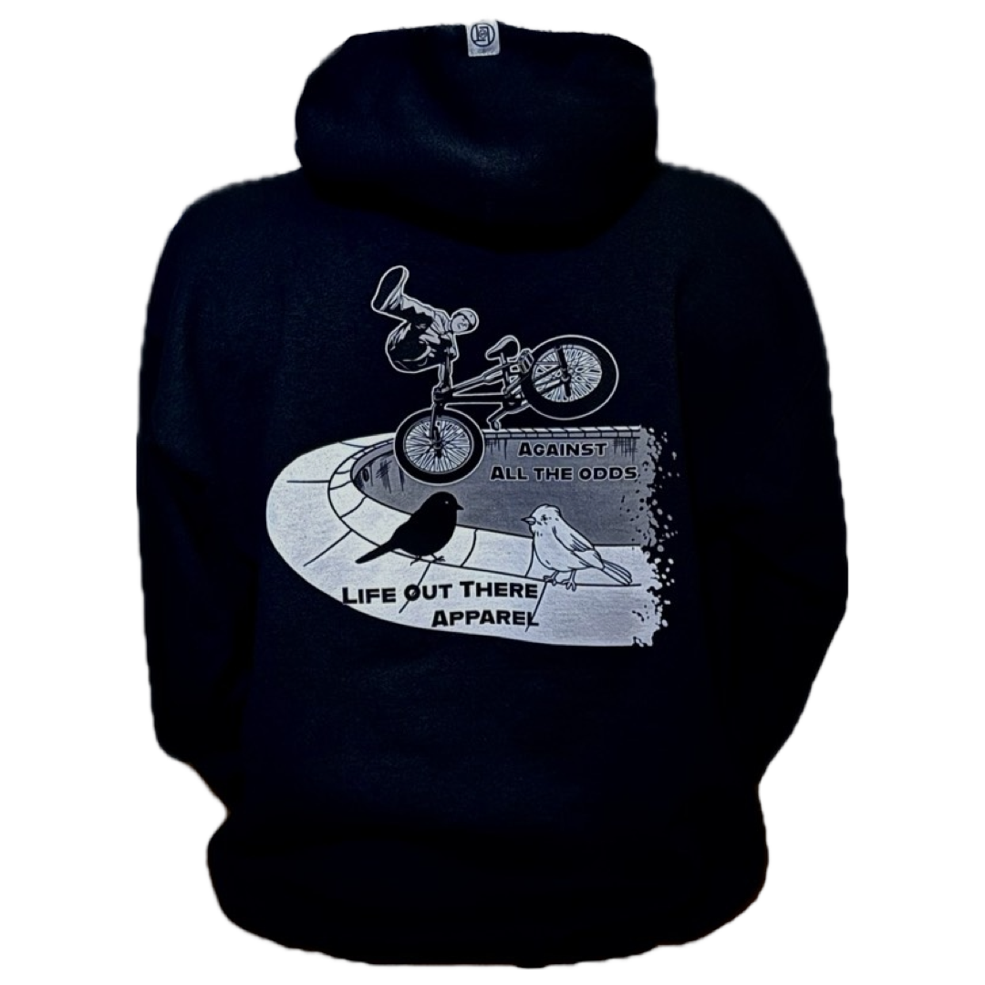 The Unisex Against All The Odds / The Ride Hoodie in black by Life Out There Apparel features a graphic of BMX rider John Buultjens, two birds, and the phrases AGAINST ALL THE ODDS and Life Out There Apparel on the back.
