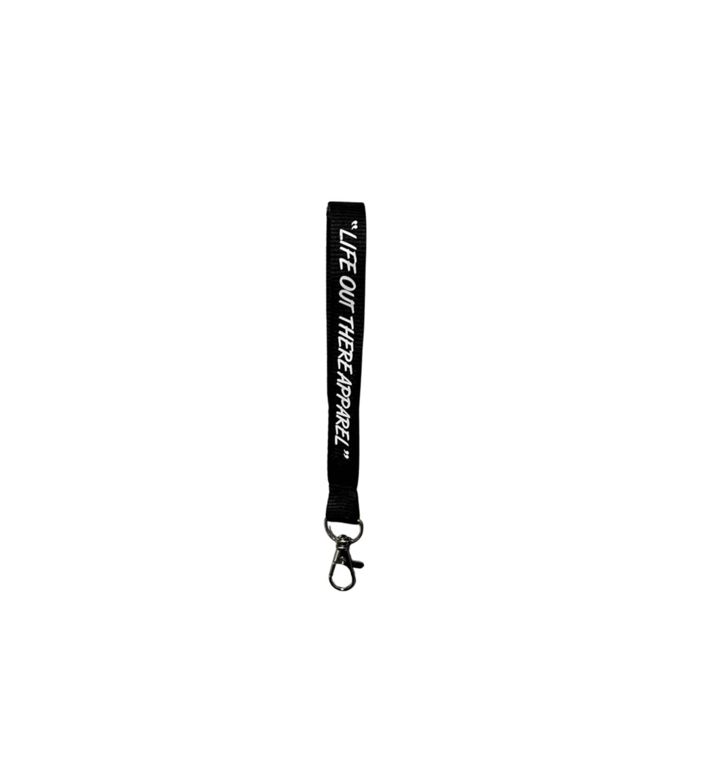 The Life Out There - Wrist Lanyard Keychain, by Life Out There Apparel, is a black wrist lanyard featuring the text "LIFE OUT THERE APPAREL" in white. It includes a metal swivel hook at the bottom.