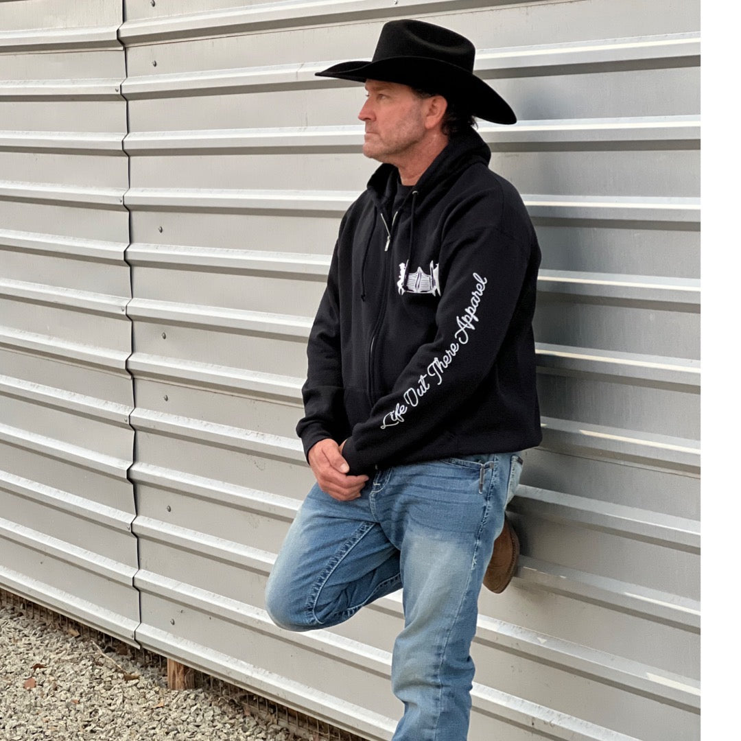 A model showcasing the black zip-up hoodie from Life Out there, featuring designs inspired by country music on the frontside.