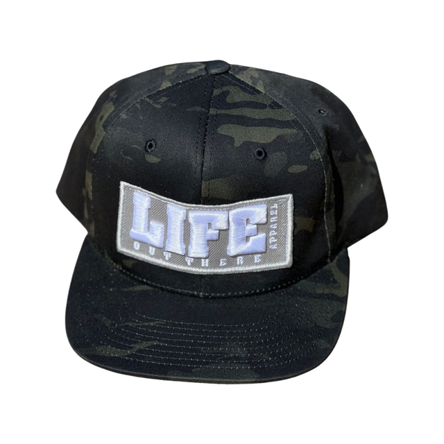 A Life Out There - Puff Embroidered SnapBack Hat in black camo from Life Out There Apparel, featuring a white embroidered front patch with the bold word "LIFE" and "OUT HERE" underneath in smaller letters.