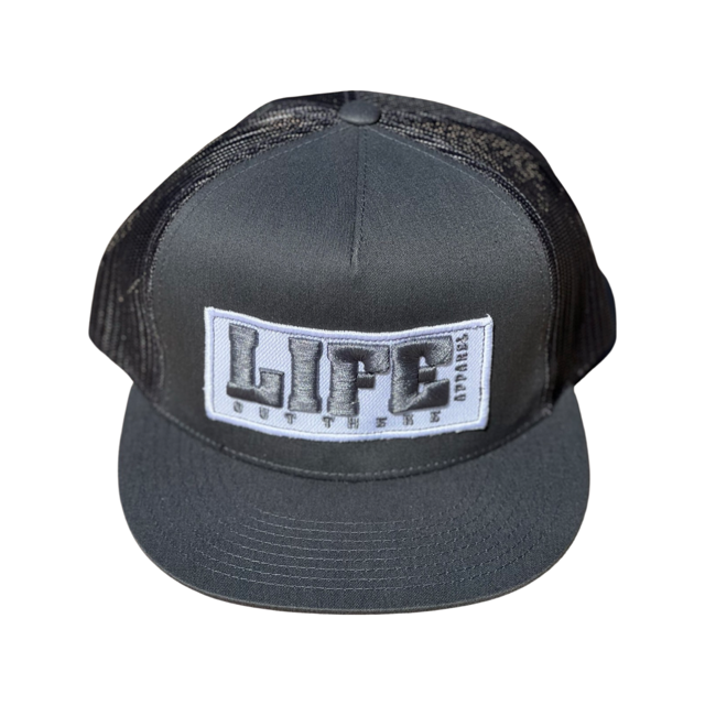 Introducing the Life Out There - Puff Embroidered SnapBack Trucker Hat in grey from Life Out There Apparel. This cap features a stylish flat brim and breathable mesh sides in that timeless trucker style. It showcases a striking design with puff embroidery boldly spelling out LIFE OUT THERE across the front, epitomizing both flair and substance.