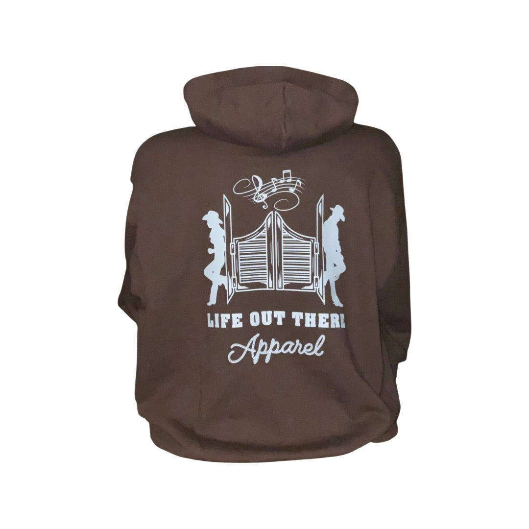 Chocolate hoodie featuring a graphic of two cowboy silhouettes with a musical note and gate in the center, celebrating country music and ranch life. Text below reads Life Out There Apparel. Product Name: Unisex THE YEEHAW Hoodie - Chocolate / White by Life Out There Apparel.