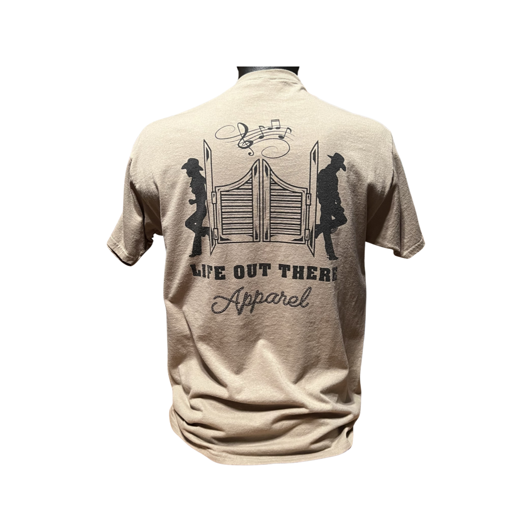 A khaki T-shirt, known as the Unisex THE YEEHAW T Shirt, showcases an illustration of swinging saloon doors with two cowboys on either side, capturing the essence of the cowboy lifestyle. Musical notes above the doors add a country music flair. The text prominently displays "Life Out There Apparel.