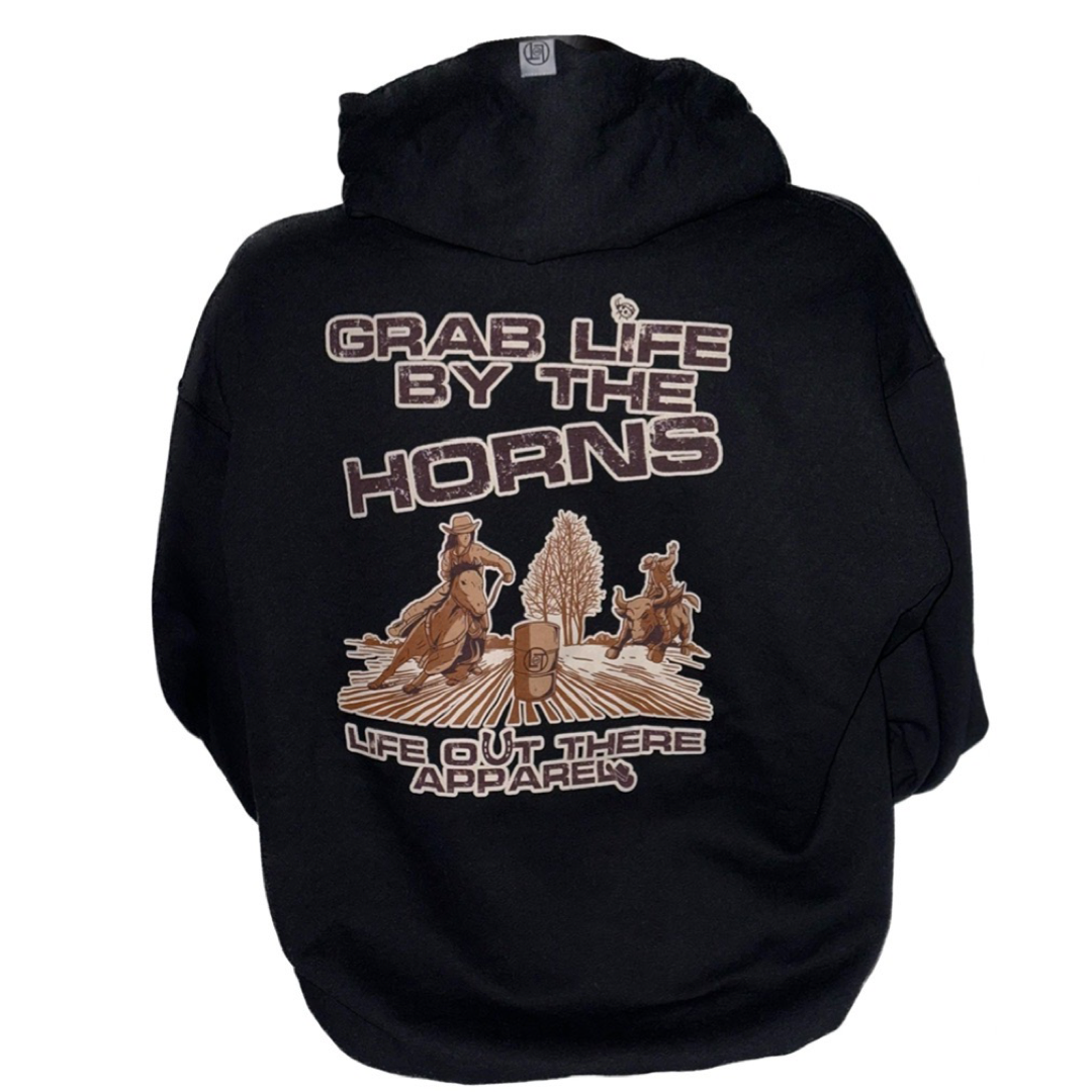 Life Out There Apparel “Grab Life By The Horns” Black Unisex Hoodie has a girl barrel racer getting ready to turn around a barrel with a guy riding a bull behind her.  This shows the back of the black hoodie with a transparent background. 