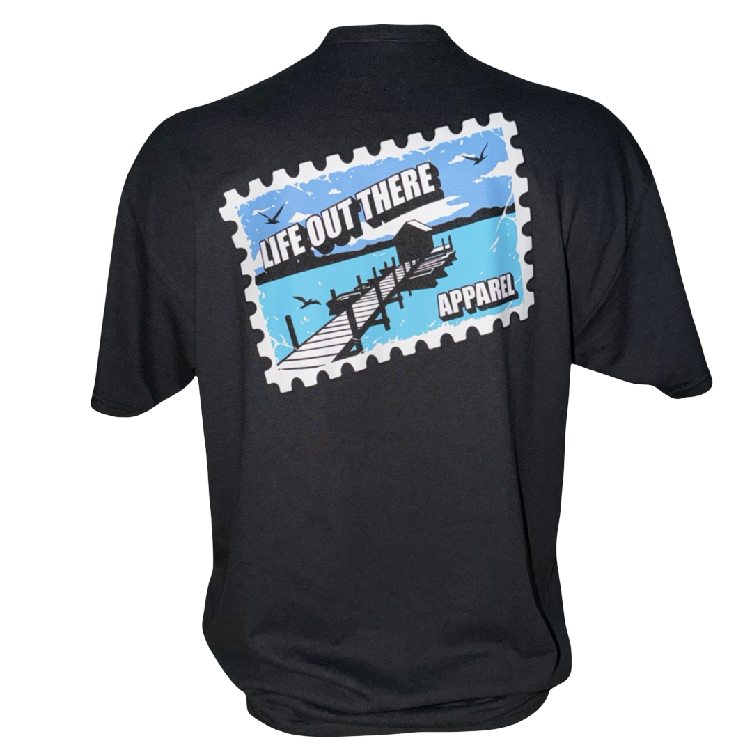 The Wish You Were Here Tee - Black by Life Out There Apparel features a postage stamp-style graphic of a dock over water with birds, and is crafted from soft cotton polyester for unisex comfort. Text reads LIFE OUT THERE APPAREL.