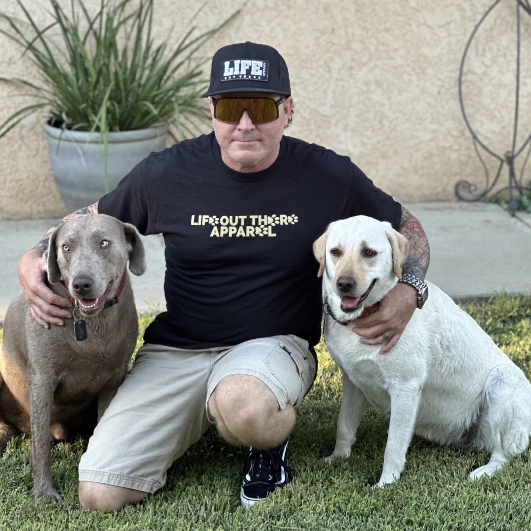 Life Out There Apparel “Best Friend” Unisex tee shirt in black. This is a guy with his best friends, a yellow & a silver Labrador. The front of the shirt has paw prints on it. This is a tribute to our dogs, our best friend is a Labrador retriever dog on a hike with his humans. 
