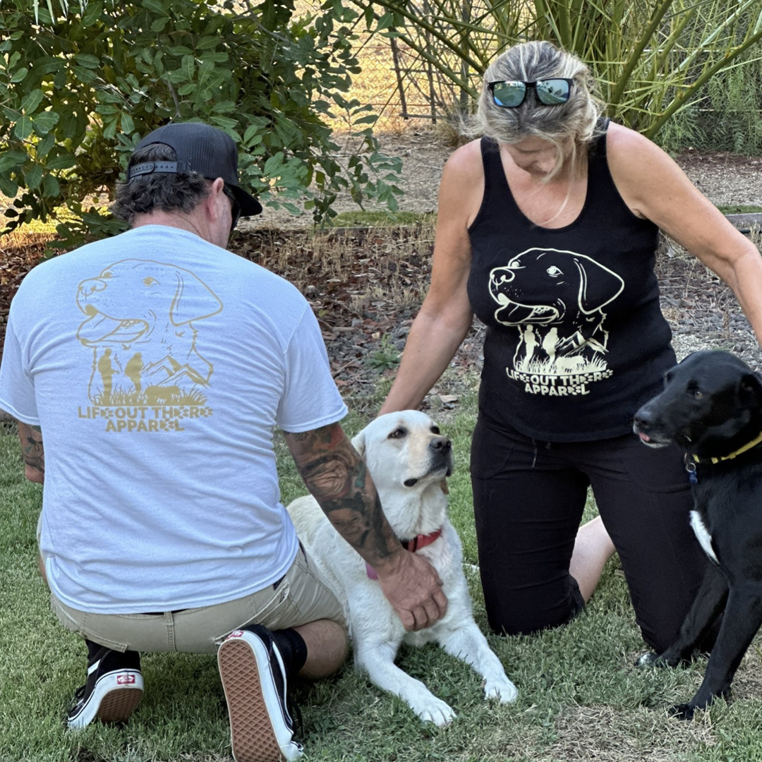 Life Out There Apparel “Best Friend” Unisex tee shirt in white with a man wearing it & a women wearing a black tank top. This is a tribute to our dogs, our best friend is a Labrador retriever dog on a hike with his humans.