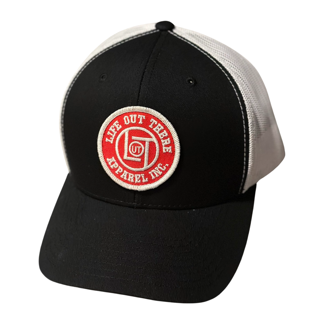 Introducing the LOT Curved Bill Snapback Trucker Hat in Black and White by Life Out There Apparel. This hat features a mesh back and showcases a circular red and white patch on the front, expertly stitched with the text "Life Out There Apparel Inc." around a central design.