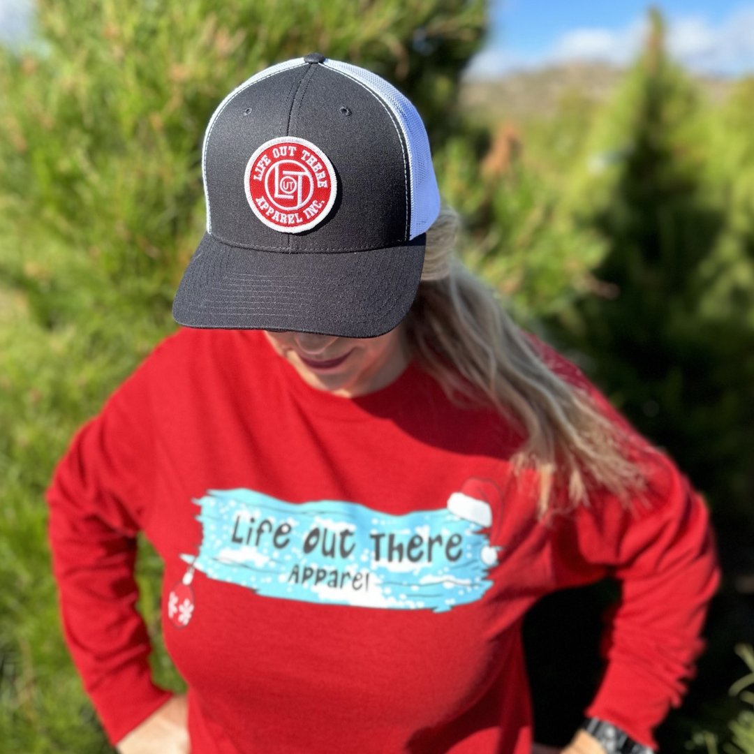 Life Out There Apparel “December 26th” red Unisex long sleeve tee shows a piece of wood covered in ice with a santa hat and an ornament hanging down from it. A women showing the front of the shirt. 