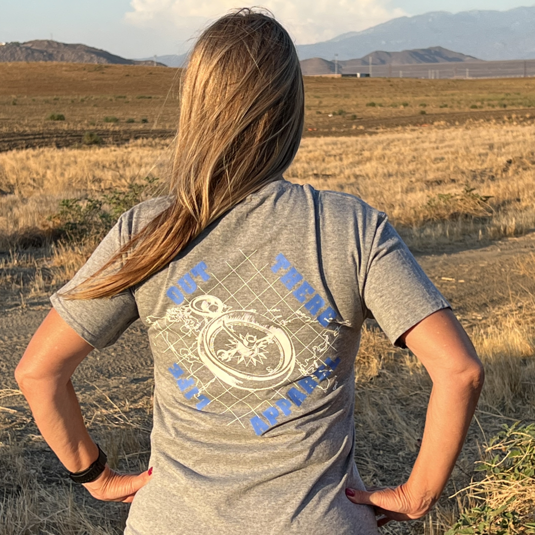 Life Out There Apparel “A New Path” Unisex Oxford grey tee shirt has a woman wearing this shirt. The design has a nautical feel with a compass on top of an atlas. This design was created in support of suicide awareness month. 