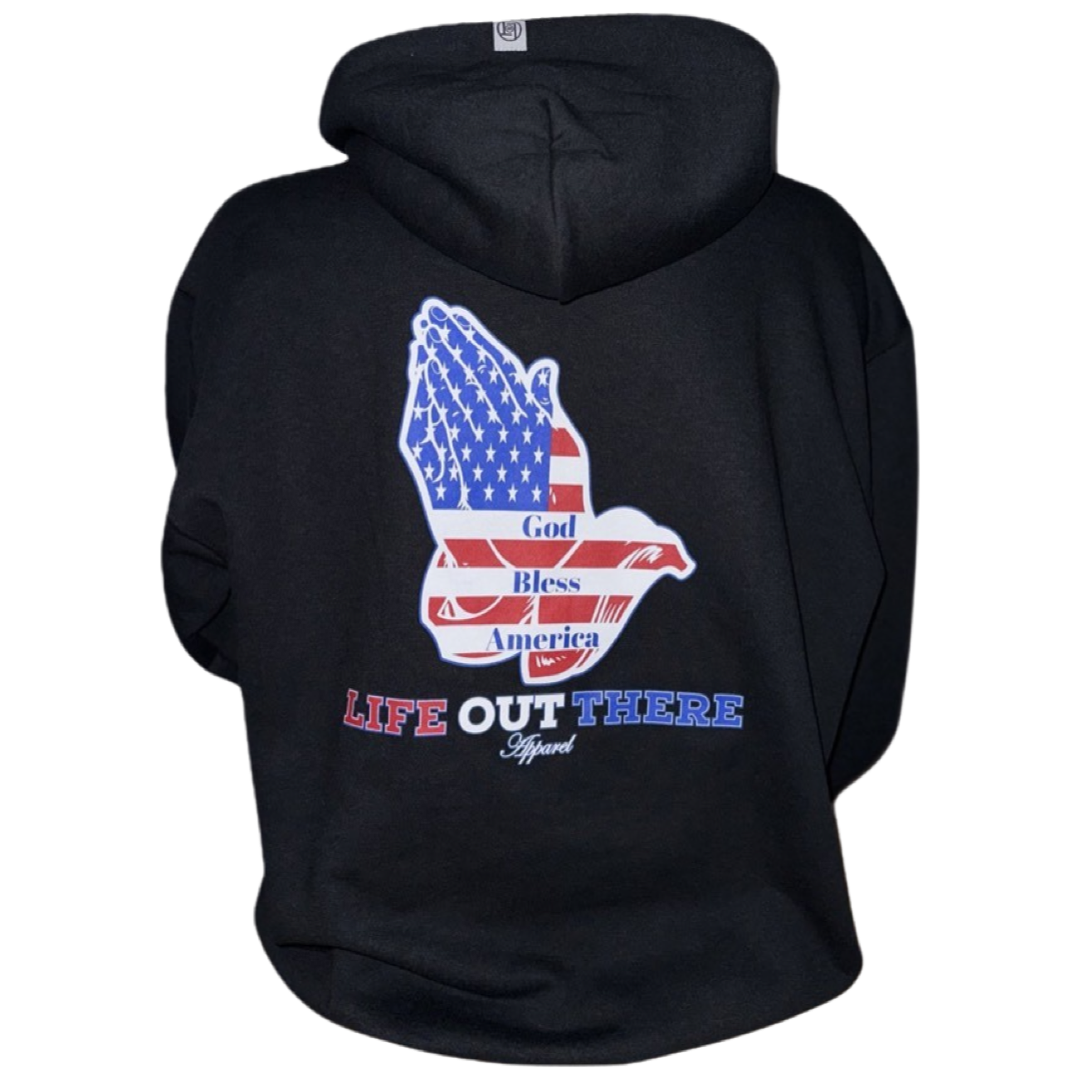 The Unisex God Bless America Hoodie in black, presented by Life Out There Apparel, features a striking back design with praying hands adorned in an American flag pattern. The text "God Bless America" makes it an ideal choice for celebrating the 4th of July.