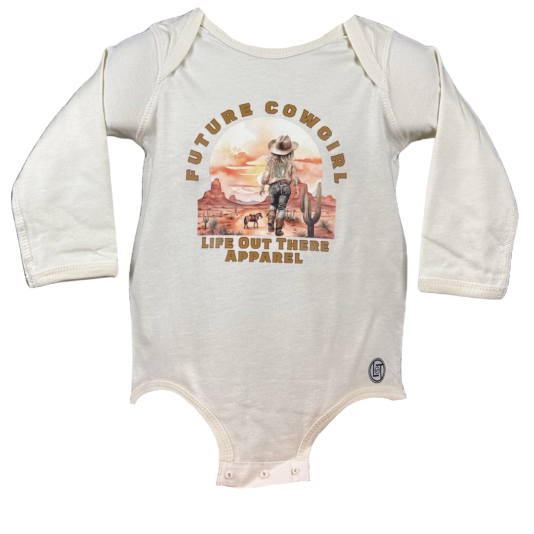 Natural beige baby onesie featuring a desert cowgirl graphic with cacti and mountains. Made from 100% cotton, it has Future Cowgirl text above and Life Out There Apparel below. Long sleeves with snap closures at the bottom, ideal for little country music fans.