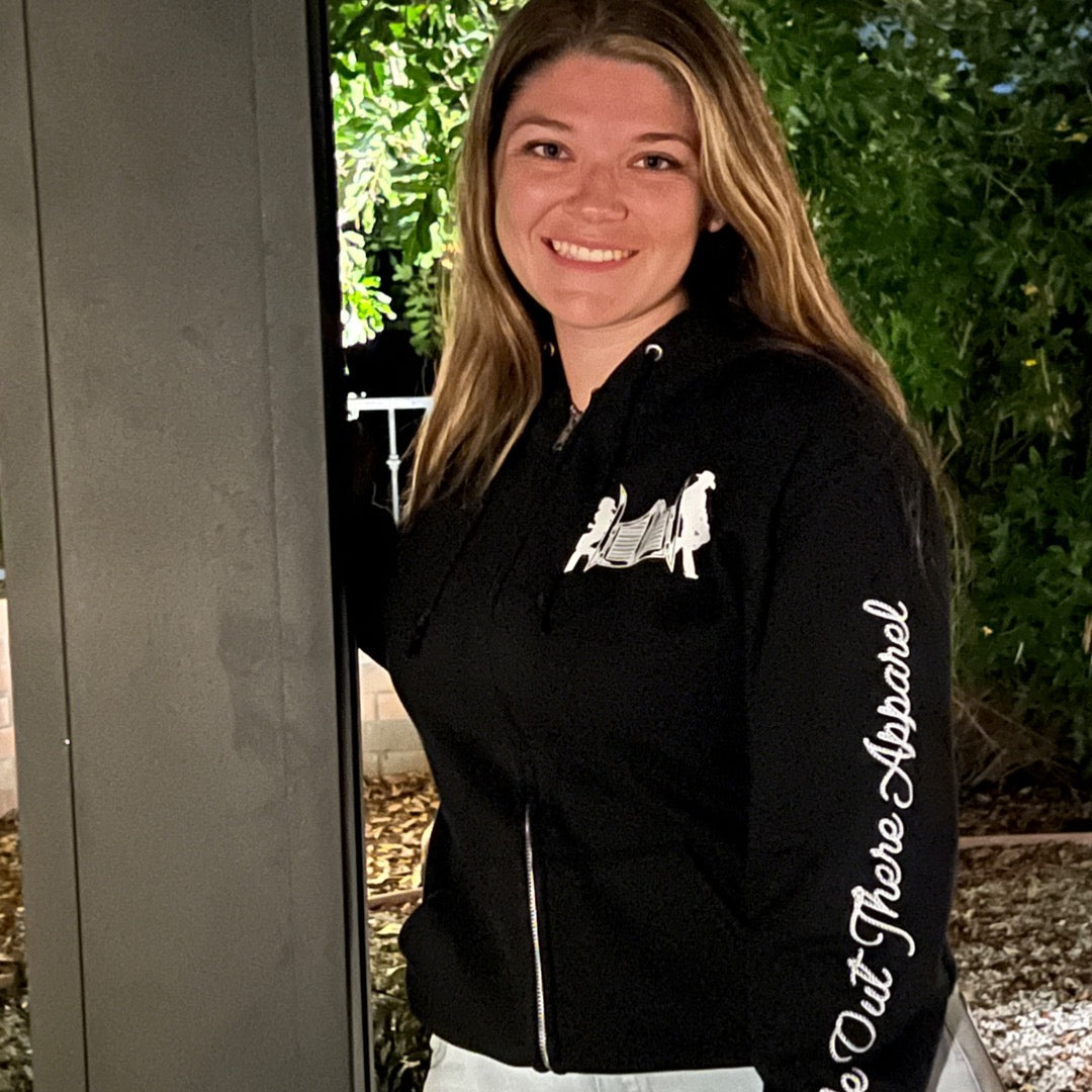 A model showcasing the black zip-up hoodie from Life Out there, featuring designs inspired by country music on the frontside.