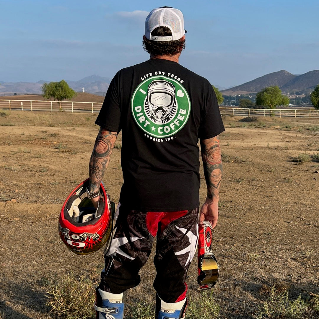Life Out There Apparel “I ❤️Dirt⭐️Coffee” Black Unisex tee shirt is a twist on a Starbucks logo with a dirt bike helmet on the siren. A man holding a pair of goggles and a motocross helmet, wearing the shirt. 