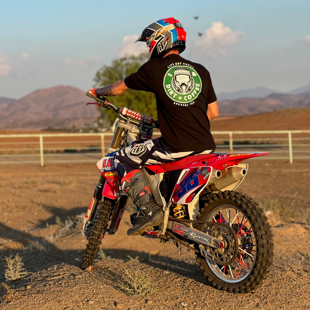 Life Out There Apparel “I ❤️Dirt⭐️Coffee” Black Unisex tee shirt is a twist on a Starbucks logo with a dirt bike helmet on the siren. A man sitting on his dirt bike, wearing the shirt.   