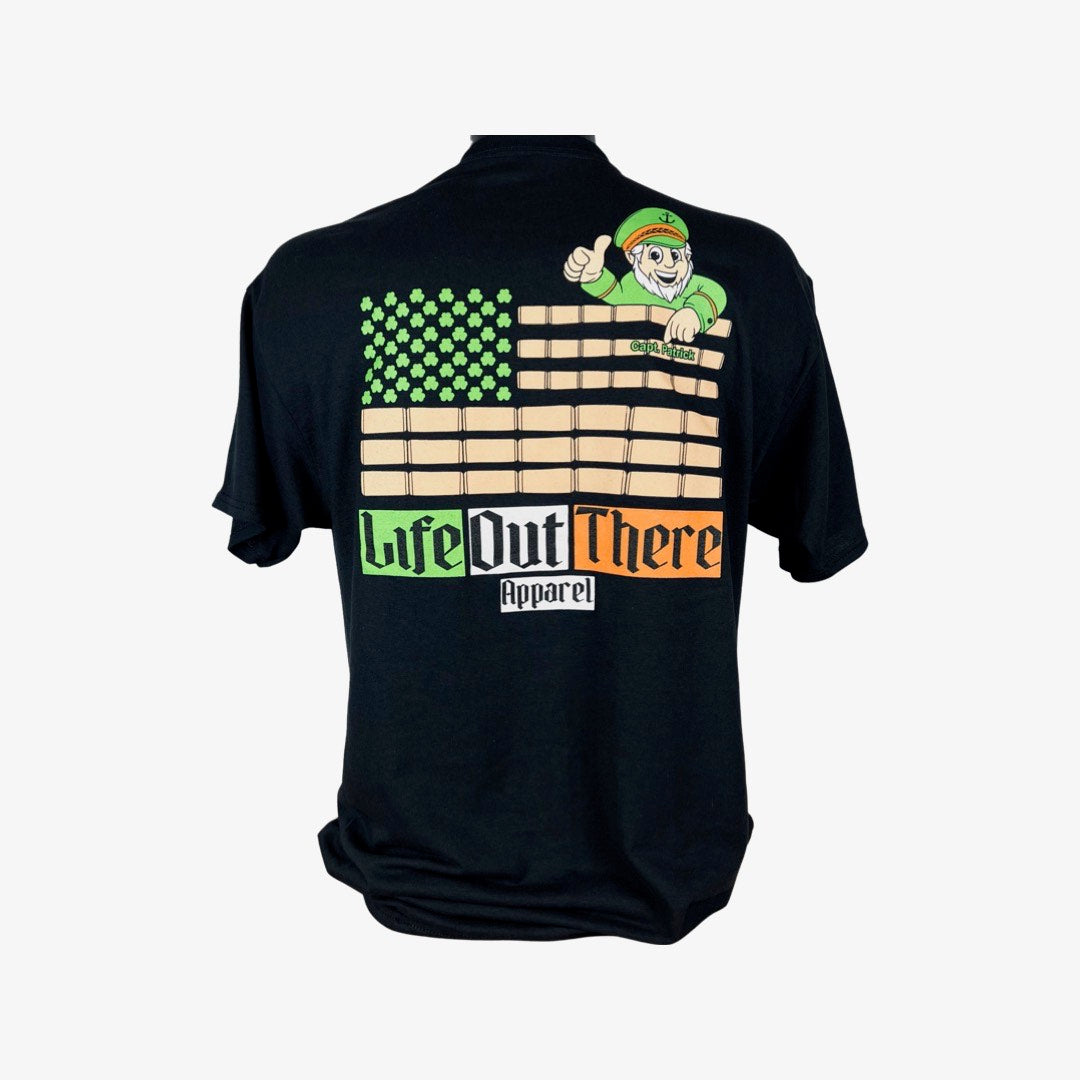 Life Out There Apparel “Capt. Patrick” Unisex black tee shirt is a collaboration of an American flag with an Irish twist and a leprechaun boat Captain looking on. With corks on it. 